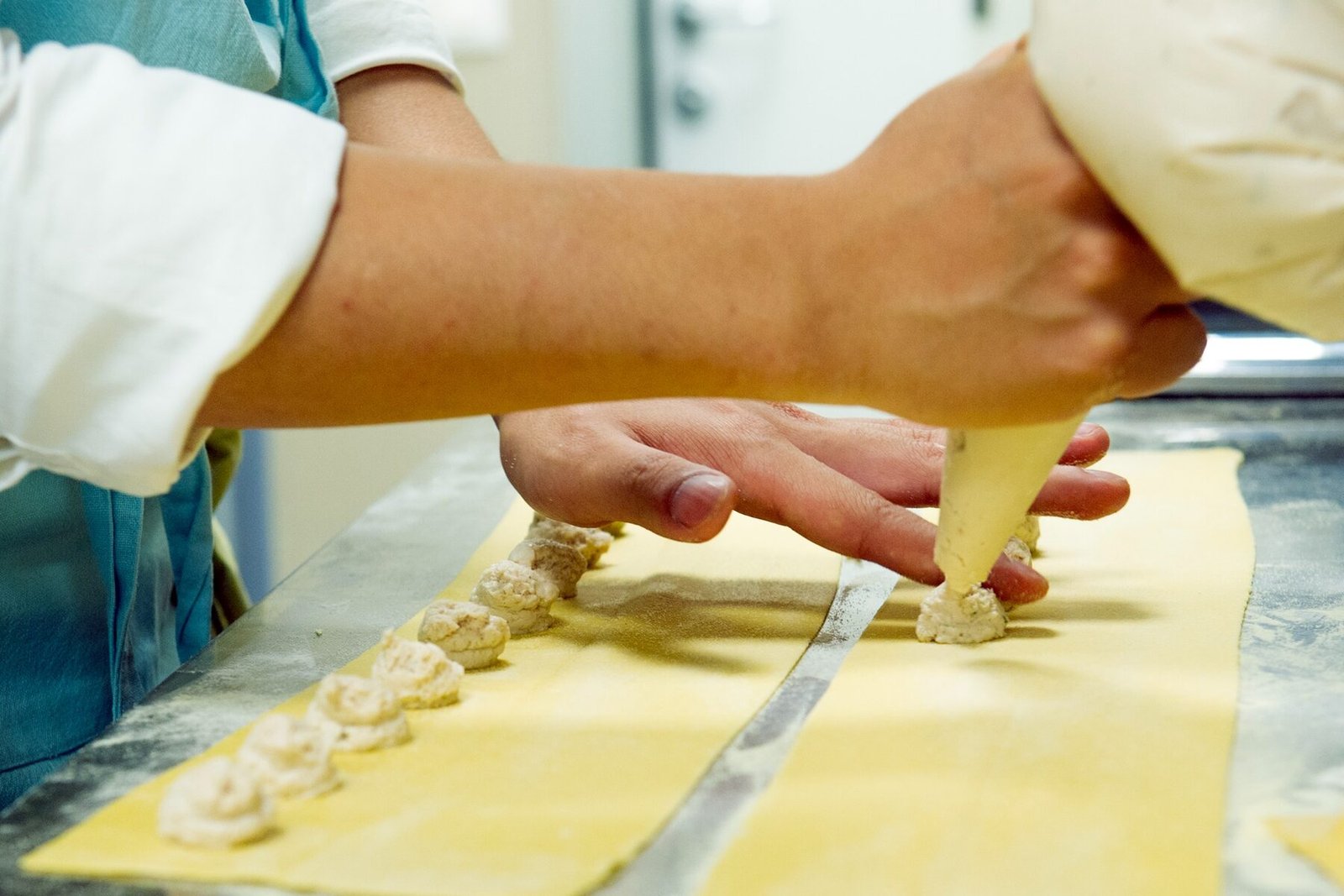 Dettaglio delle mani e della sac à poche sulla pasta