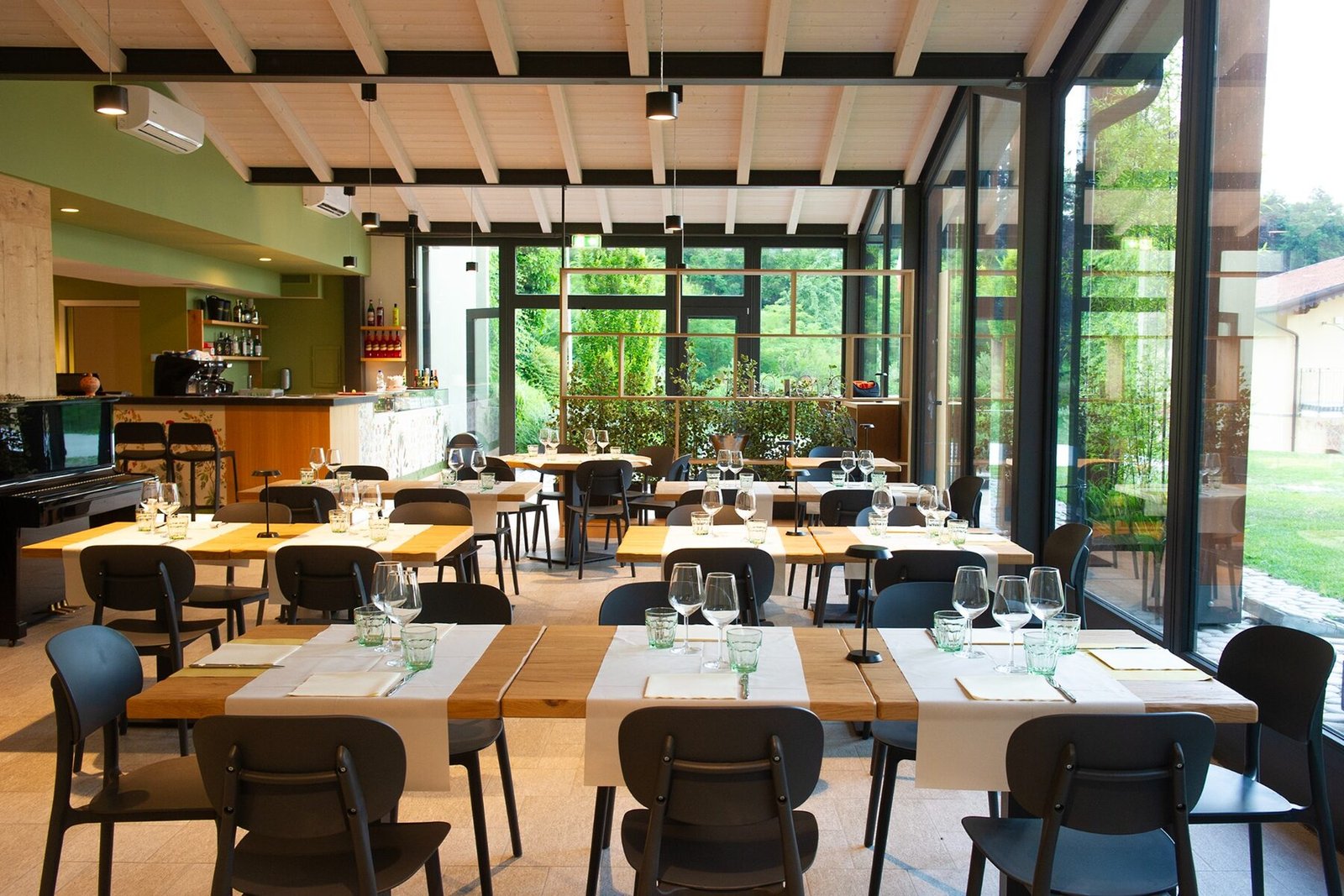 I tavoli della sala e le vetrate che si aprono sul verde